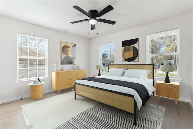 bedroom with hardwood / wood-style floors, multiple windows, and ceiling fan