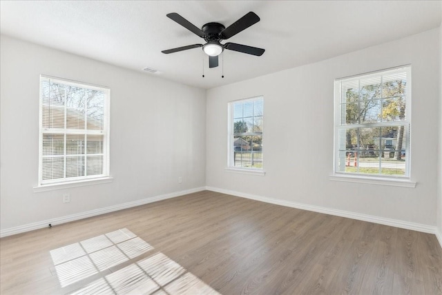 empty room with ceiling fan, a healthy amount of sunlight, and light hardwood / wood-style flooring