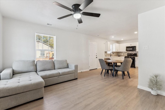 living room featuring ceiling fan and light hardwood / wood-style floors