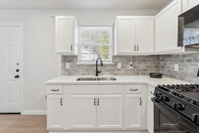 kitchen with black appliances, a healthy amount of sunlight, white cabinetry, and sink