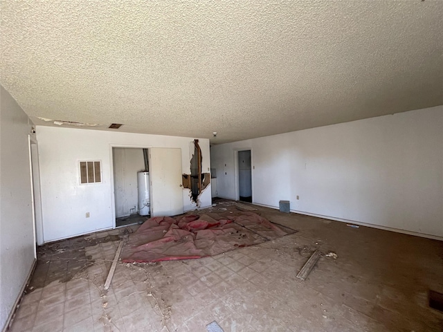 unfurnished living room featuring gas water heater and a textured ceiling