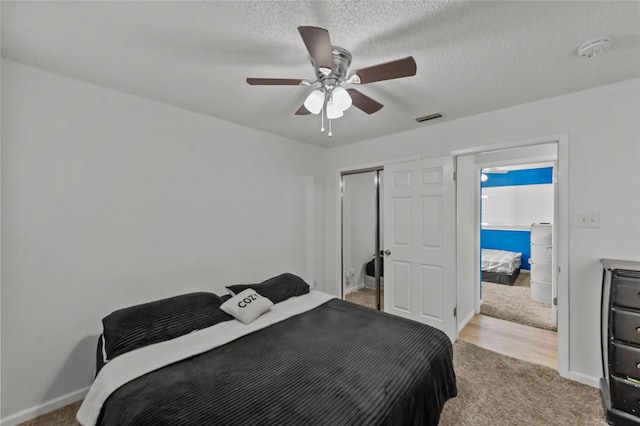 bedroom with a textured ceiling, light colored carpet, and ceiling fan