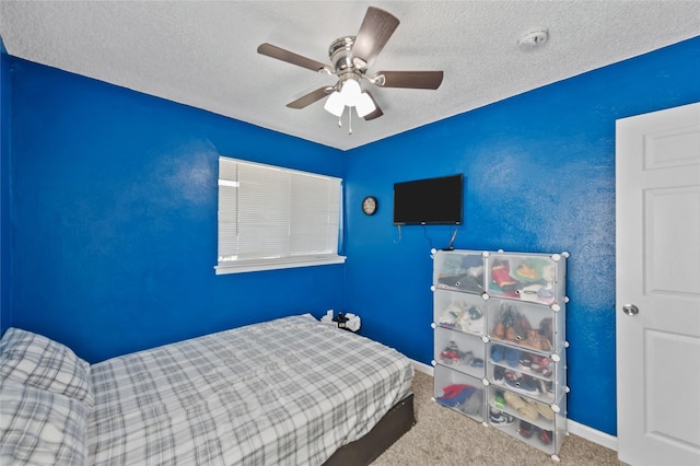 bedroom with ceiling fan, carpet floors, and a textured ceiling