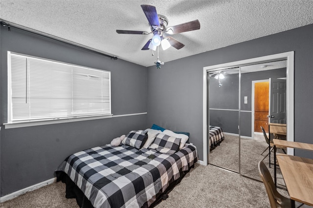 carpeted bedroom with ceiling fan, a closet, and a textured ceiling