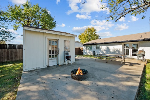 rear view of property with french doors, a fire pit, a storage shed, and a patio area