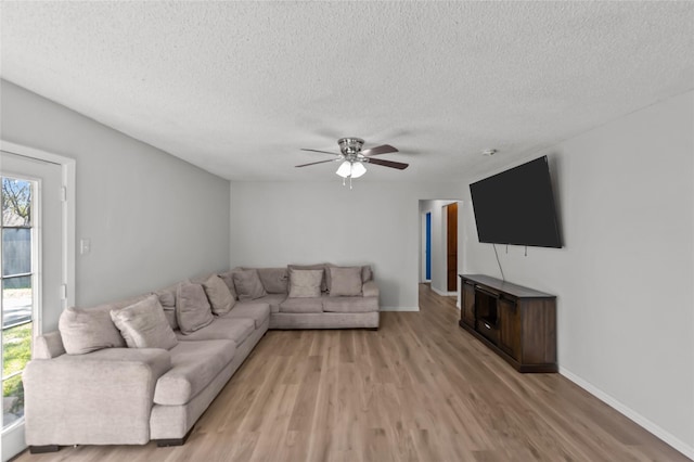 living room featuring a textured ceiling, light hardwood / wood-style flooring, and ceiling fan