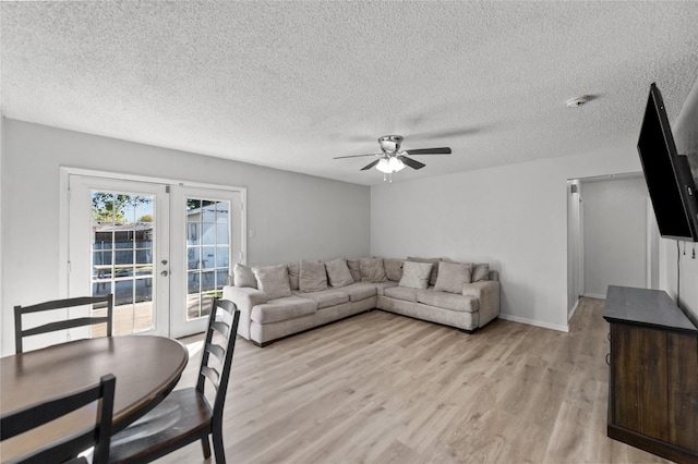 living room featuring a textured ceiling, light wood-type flooring, french doors, and ceiling fan