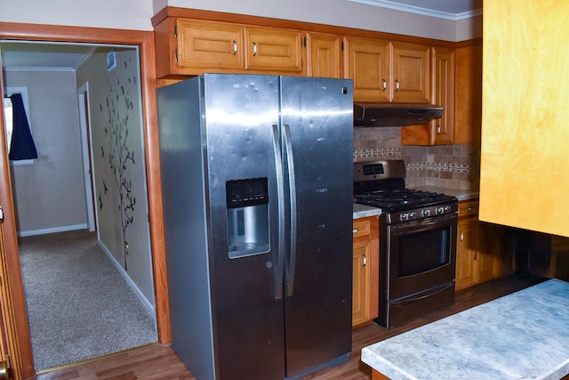 kitchen with backsplash, ornamental molding, stainless steel appliances, and hardwood / wood-style flooring