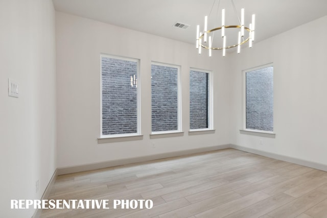 spare room with light hardwood / wood-style flooring and a notable chandelier