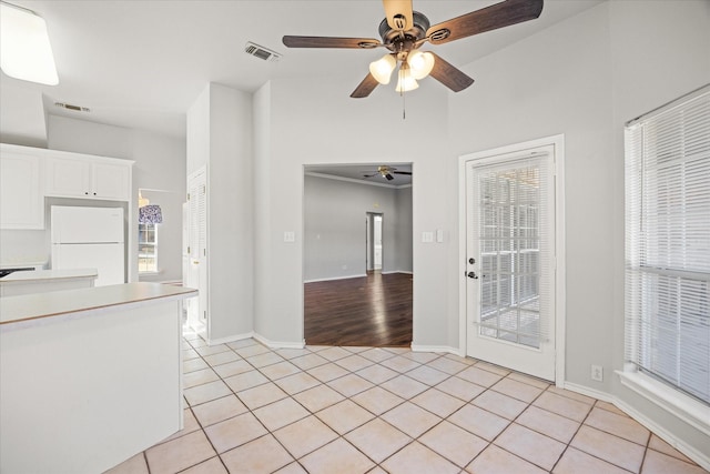 interior space featuring white refrigerator, white cabinetry, ceiling fan, and light tile patterned floors