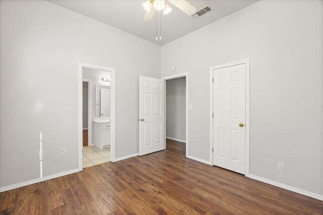 unfurnished bedroom featuring ensuite bath and hardwood / wood-style floors