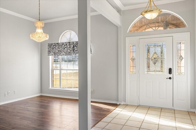 foyer entrance with hardwood / wood-style floors, ornamental molding, and a chandelier