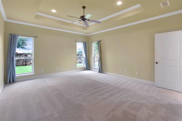 carpeted empty room with a tray ceiling, ceiling fan, and crown molding