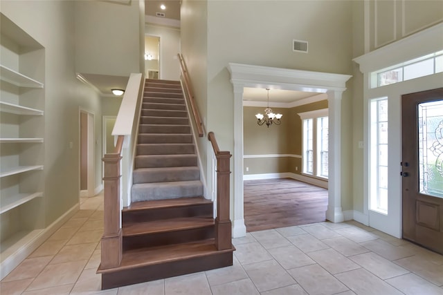 tiled foyer entrance featuring a high ceiling, an inviting chandelier, and ornamental molding