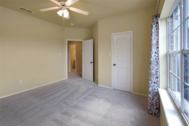 unfurnished room with ceiling fan, light colored carpet, and a wealth of natural light