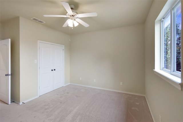 unfurnished bedroom with ceiling fan, light colored carpet, and multiple windows