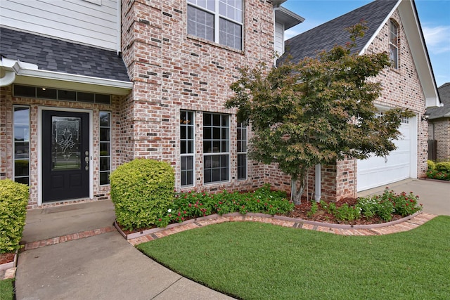 doorway to property with a garage and a yard