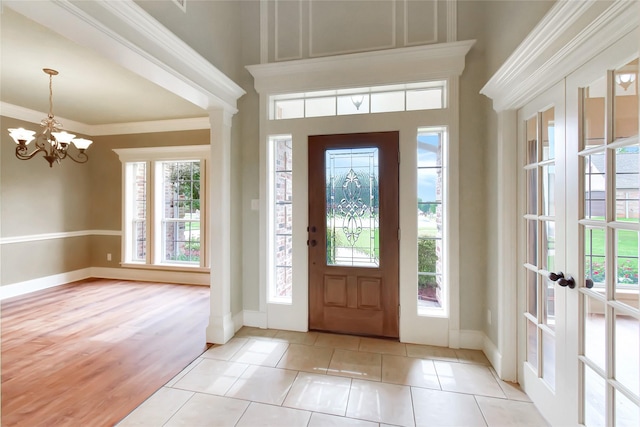 entryway with a wealth of natural light, crown molding, a chandelier, and light hardwood / wood-style flooring