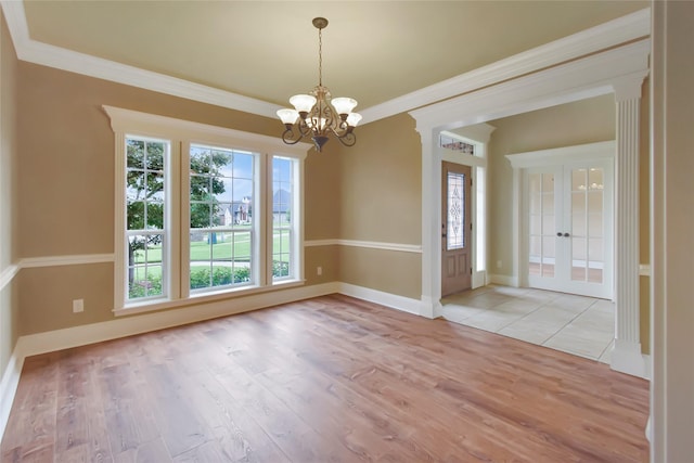 interior space featuring ornamental molding, plenty of natural light, light hardwood / wood-style floors, and a notable chandelier