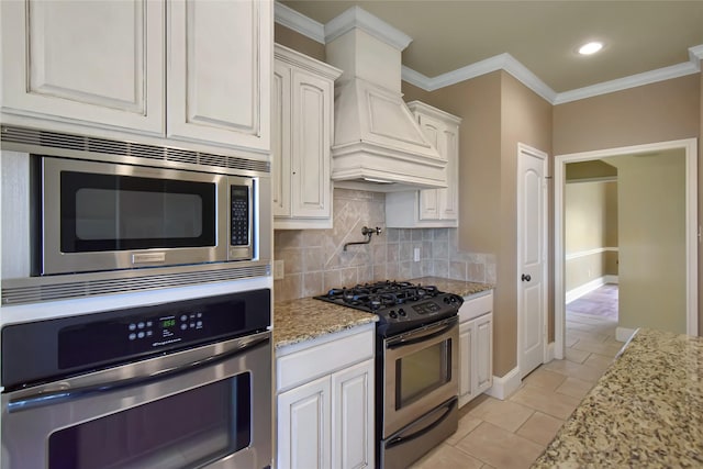 kitchen with white cabinets, crown molding, premium range hood, and stainless steel appliances