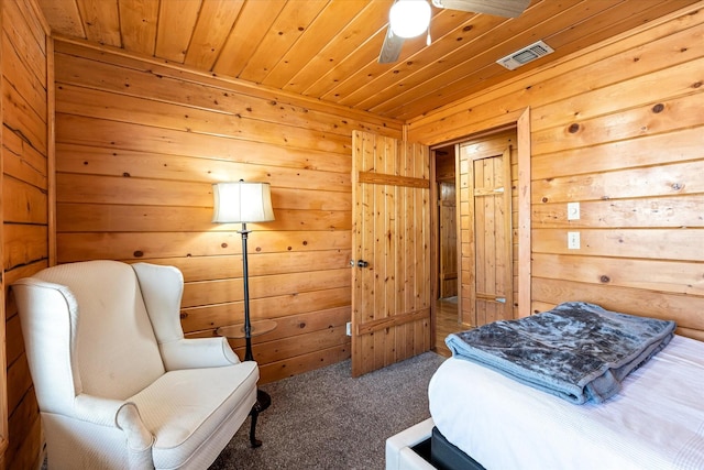 bedroom with ceiling fan, wood walls, carpet floors, and wood ceiling