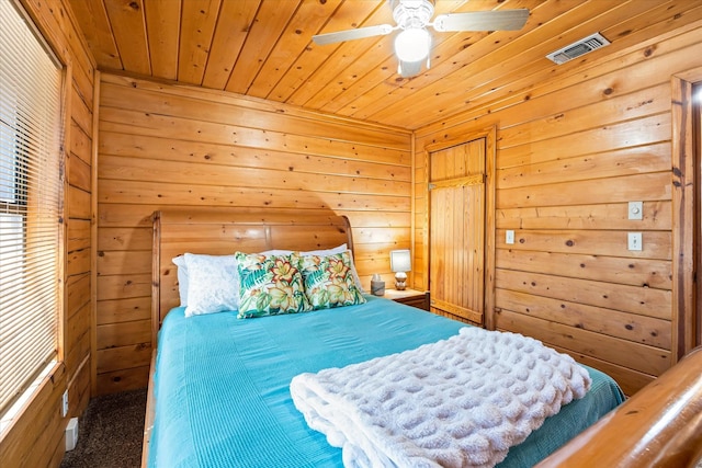 carpeted bedroom with wooden walls, ceiling fan, and wood ceiling