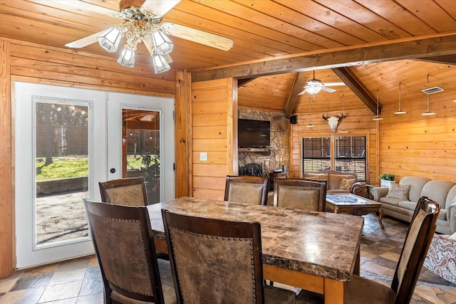 dining space featuring vaulted ceiling with beams, wooden walls, wooden ceiling, and ceiling fan