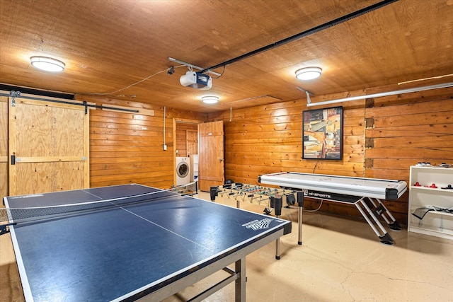 playroom featuring washer / clothes dryer, wooden walls, wooden ceiling, and a barn door