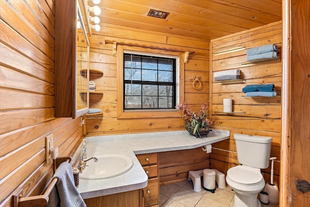 bathroom with tile patterned floors, wooden walls, vanity, and toilet