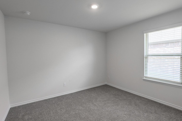 unfurnished room with dark colored carpet