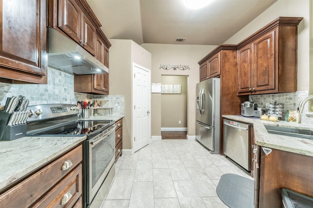 kitchen with tasteful backsplash, light stone counters, stainless steel appliances, sink, and light tile patterned floors