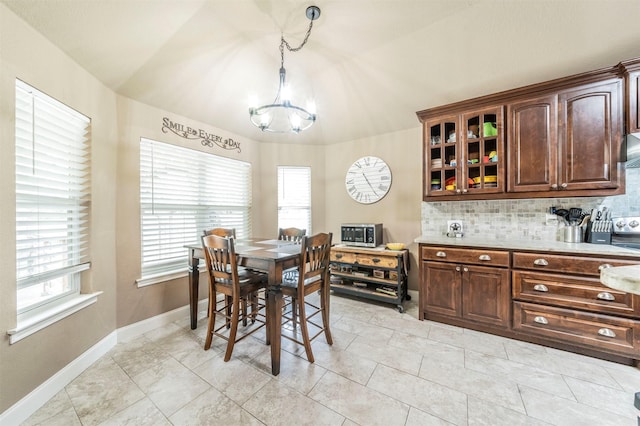 tiled dining room with vaulted ceiling and an inviting chandelier