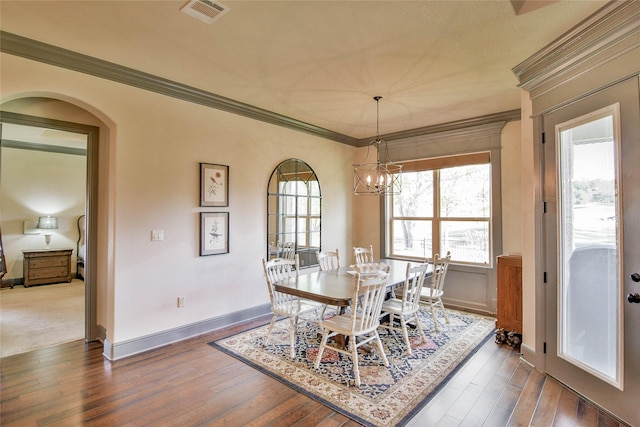 dining space with dark hardwood / wood-style floors, ornamental molding, and a chandelier