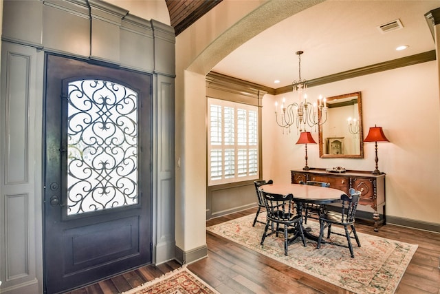 entryway with dark hardwood / wood-style floors, crown molding, and a chandelier