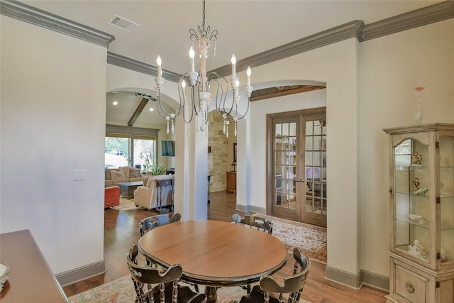 dining room featuring a notable chandelier, french doors, crown molding, and light hardwood / wood-style flooring