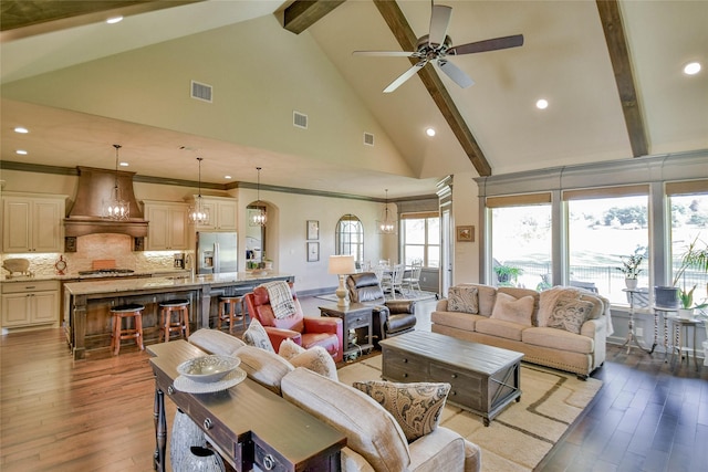 living room featuring ceiling fan with notable chandelier, beam ceiling, light wood-type flooring, and high vaulted ceiling