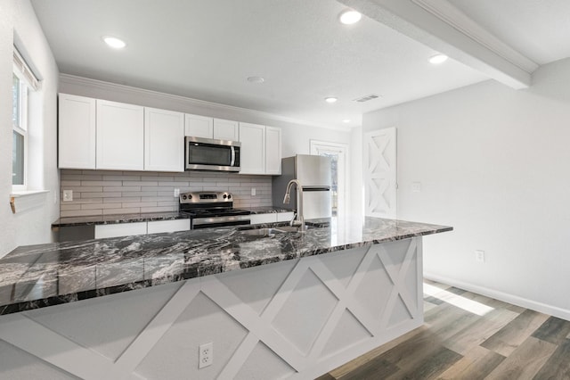 kitchen with white cabinetry, appliances with stainless steel finishes, sink, and dark stone counters