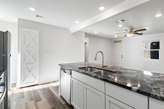 kitchen featuring appliances with stainless steel finishes, hardwood / wood-style floors, white cabinetry, sink, and dark stone countertops