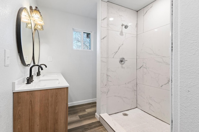 bathroom with wood-type flooring, vanity, and a tile shower