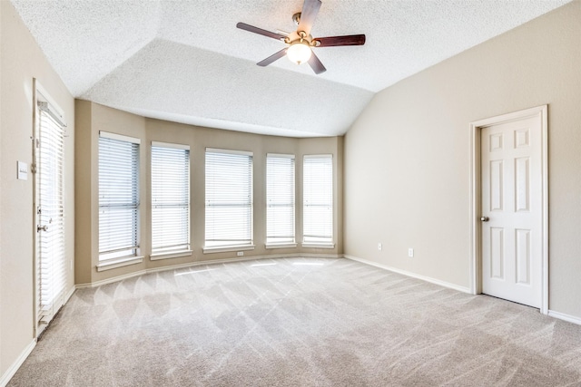 empty room with a textured ceiling, light colored carpet, ceiling fan, and lofted ceiling