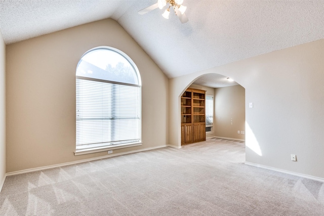 empty room with light carpet, a textured ceiling, and vaulted ceiling