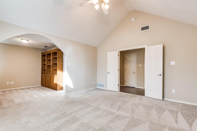 carpeted empty room with ceiling fan, high vaulted ceiling, and a textured ceiling