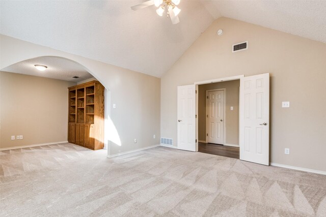 spare room featuring light carpet, a textured ceiling, high vaulted ceiling, and ceiling fan