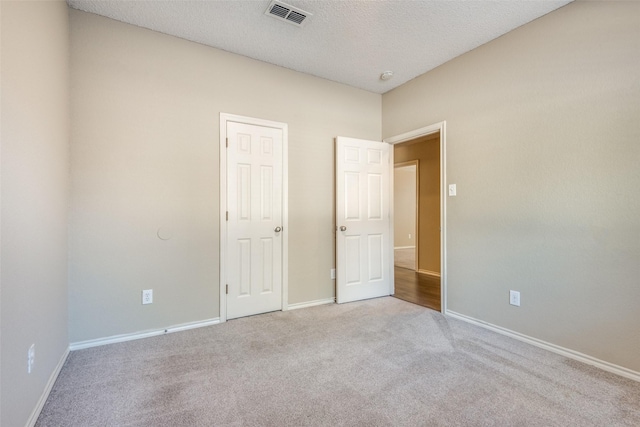 unfurnished bedroom featuring light colored carpet and a textured ceiling