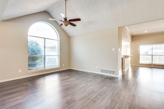 unfurnished living room featuring ceiling fan, vaulted ceiling, a healthy amount of sunlight, and dark hardwood / wood-style flooring