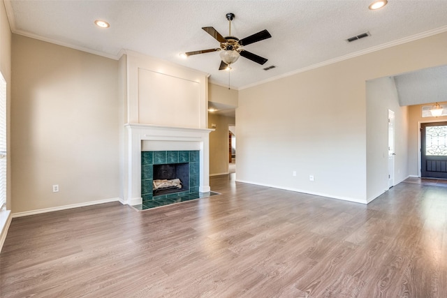 unfurnished living room with hardwood / wood-style floors, a textured ceiling, and a tiled fireplace