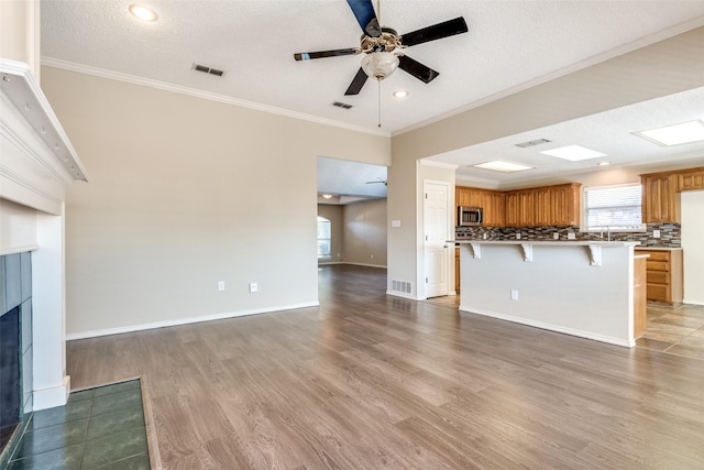 unfurnished living room featuring a textured ceiling, light hardwood / wood-style flooring, and ornamental molding