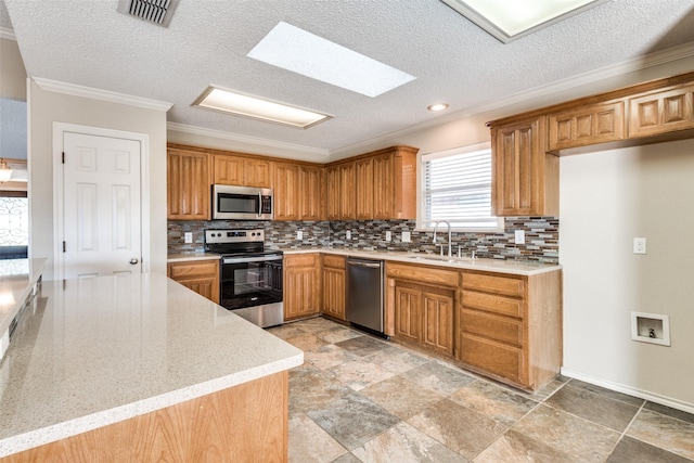 kitchen with a skylight, crown molding, a textured ceiling, and appliances with stainless steel finishes