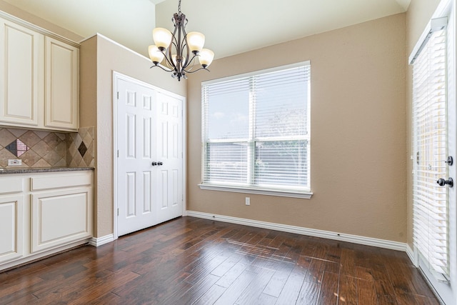 unfurnished dining area with a notable chandelier and dark hardwood / wood-style floors