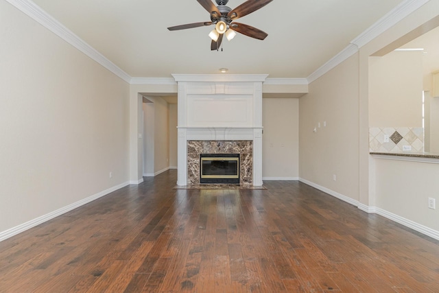 unfurnished living room featuring dark hardwood / wood-style flooring, crown molding, a fireplace, and ceiling fan